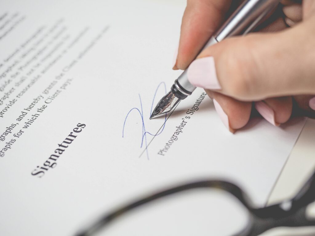 pexels-photo-175045-175045 Close-up of a hand signing a contract, showcasing a pen and elegant handwriting.